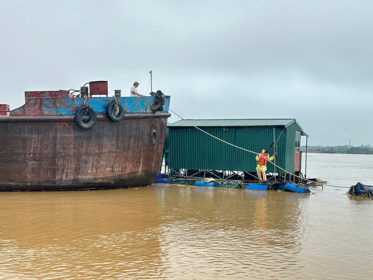 Lực lượng chức năng đ&atilde; tiếp cận đưa th&agrave;nh c&ocirc;ng hai nh&agrave; nổi v&agrave; người d&acirc;n c&ugrave;ng lồng nu&ocirc;i c&aacute; gặp nạn v&agrave;o bờ cố định an to&agrave;n